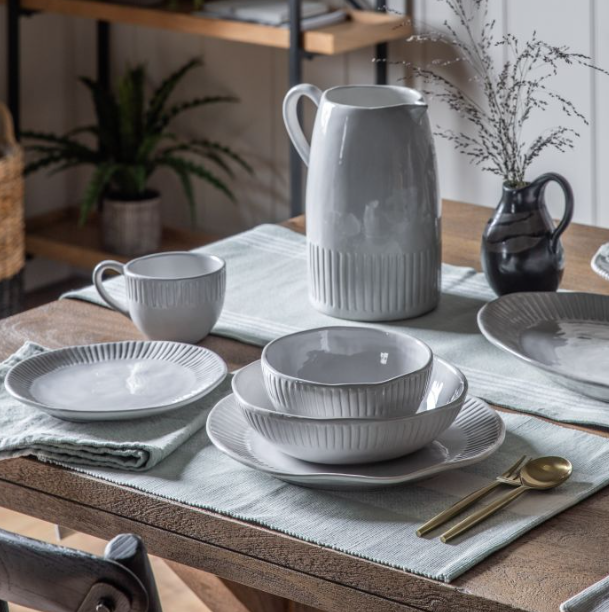 White ceramic pasta bowl with ribbed detailing and wide shallow shape on a table setting