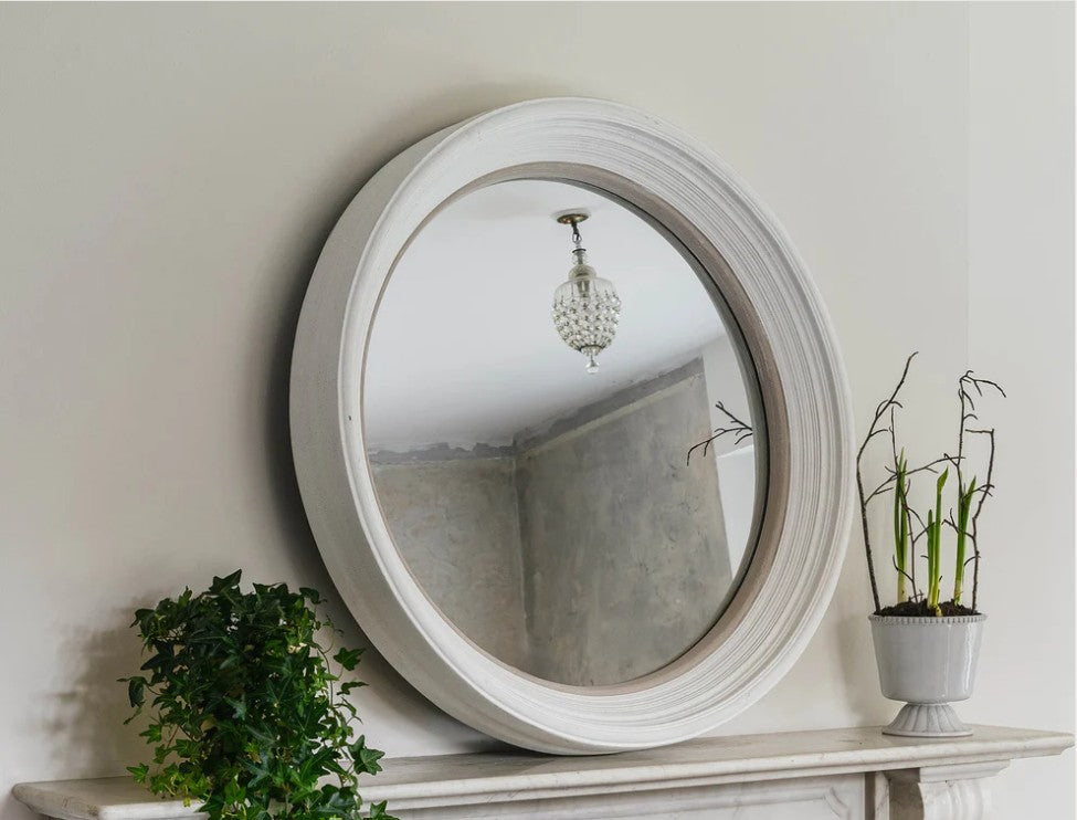 Round Wilton Portal Mirror placed above a marble fireplace, reflecting a chandelier and adding elegant depth to the room décor.