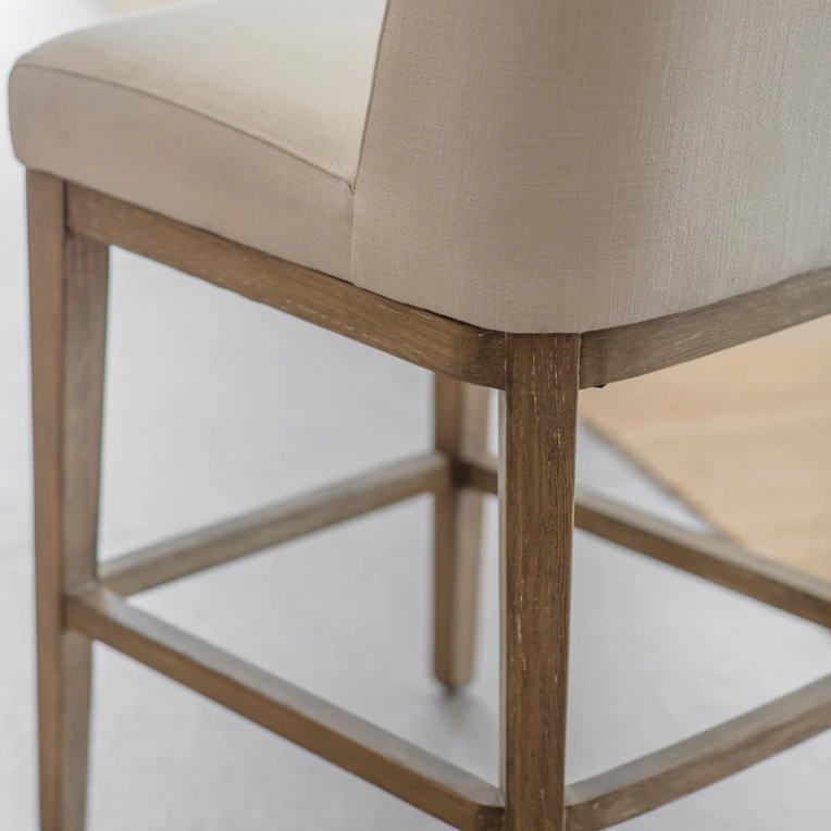 Close-up of a chair with wooden frame and beige cushioned seat on a light background
