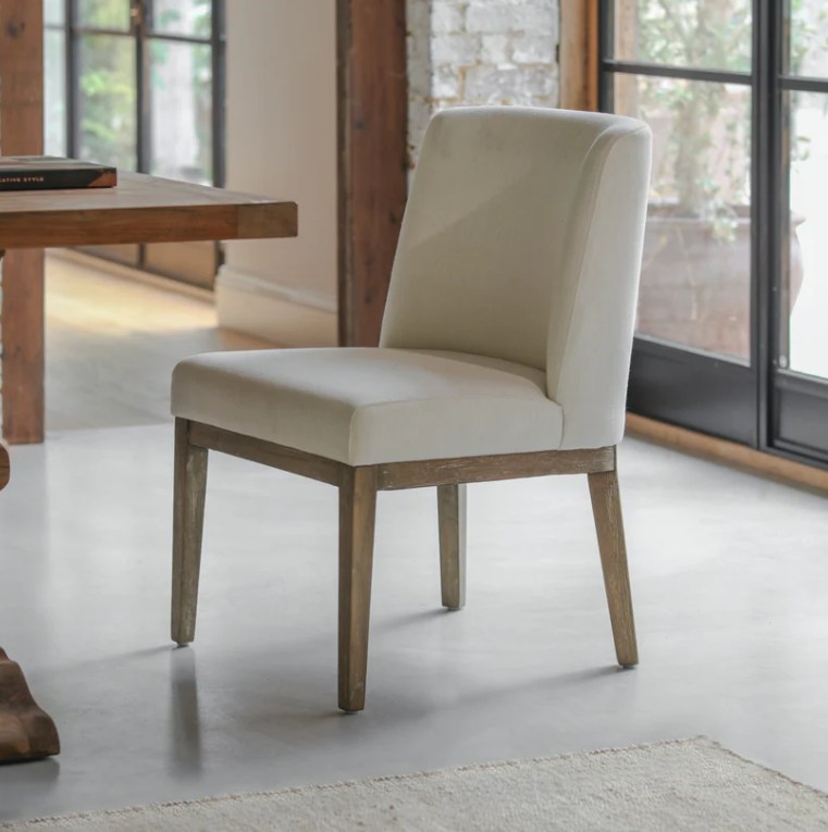Natural linen dining chair with solid wood legs in a modern dining room setting