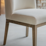 Beige upholstered chair with wooden legs on a light background