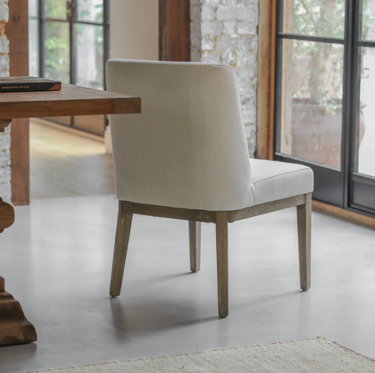 Natural linen dining chair with solid wood legs in a modern dining room setting