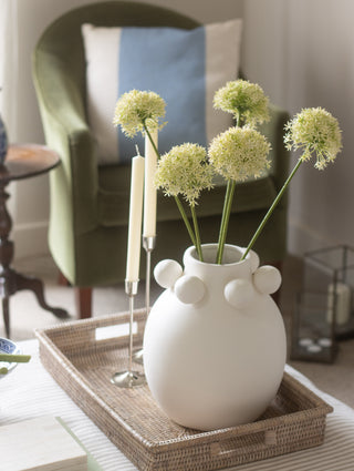 White vase with decorative flowers on a tray in a living room setting