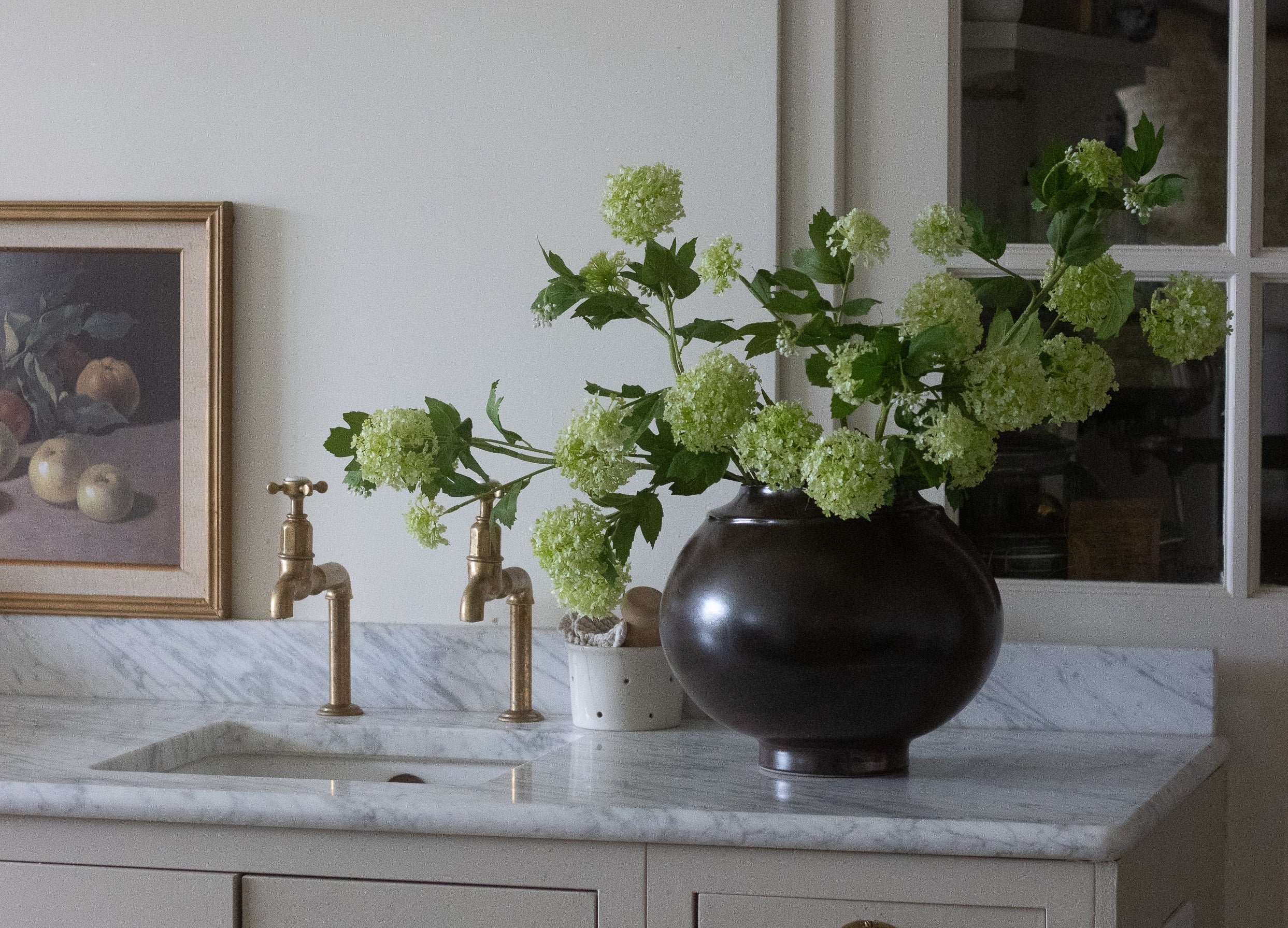 Kitchen with marble countertop, vase with green flowers, and framed picture on wall.
