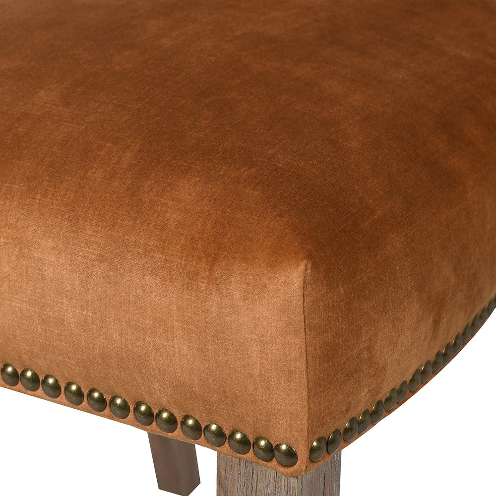 Close up of brass stud detailing on the orange velvet chair
