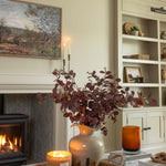 Faux burgundy eucalyptus stem styled in neutral living room