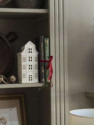 ceramic dutch house styled on a bookshelf for christmas