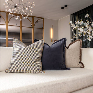 Frampton cushion layered with neutral cushions on a white sofa