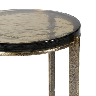 Round side table with  glass top and bronze metal base on a white background