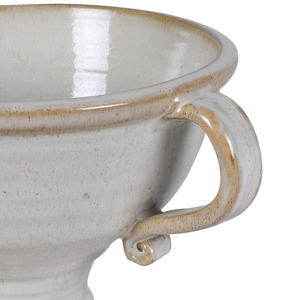 Close-up of a ceramic footed vase with a handle on a white background