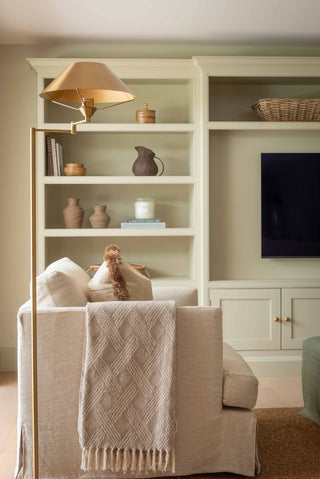 Living room with beige sofa, bookshelf, and television.