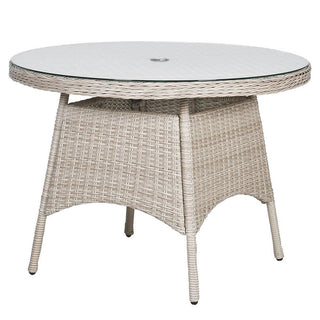 Round outdoor table with wicker frame and glass top on a white background