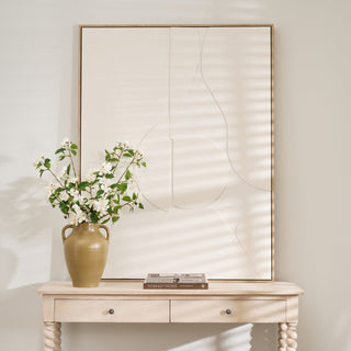 Decorative console table with a vase of flowers and books against a wall with abstract art.