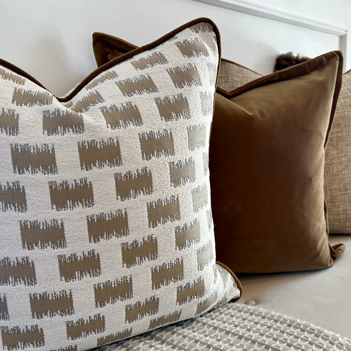 Lavenham geometric cushion styled with neutral and velvet cushions on a sofa