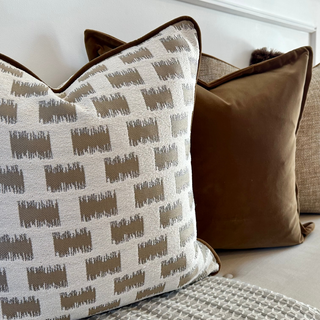 Lavenham geometric cushion styled with neutral and velvet cushions on a sofa