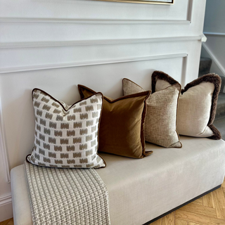 Lavenham cushion styled on a bench beneath framed artwork