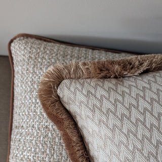 Close up of the woven geometric front and gold fringe on the Lechlade cushion