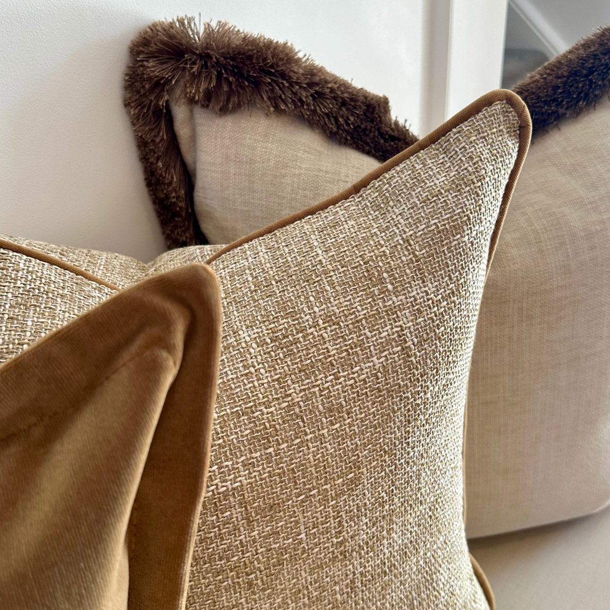 Wellow gold cushion layered with velvet and cream cushions on a sofa