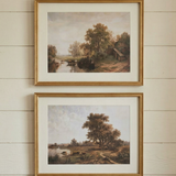 Set of two framed landscape art prints featuring pastoral countryside scenes in classic wooden frames