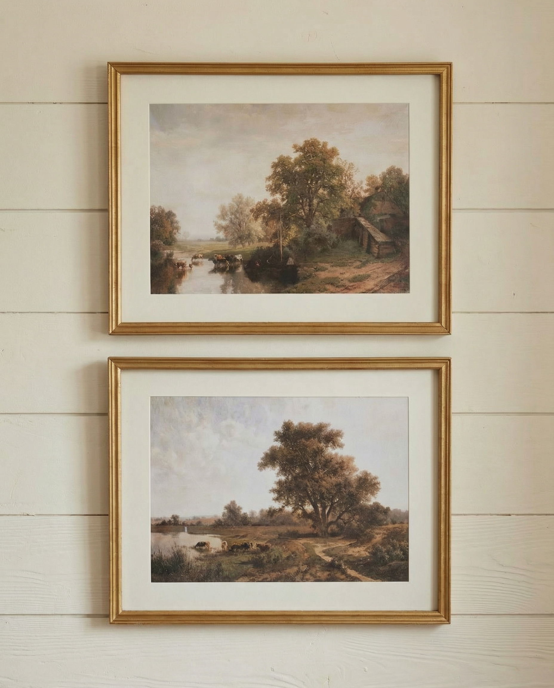 Set of two framed landscape art prints featuring pastoral countryside scenes in classic wooden frames
