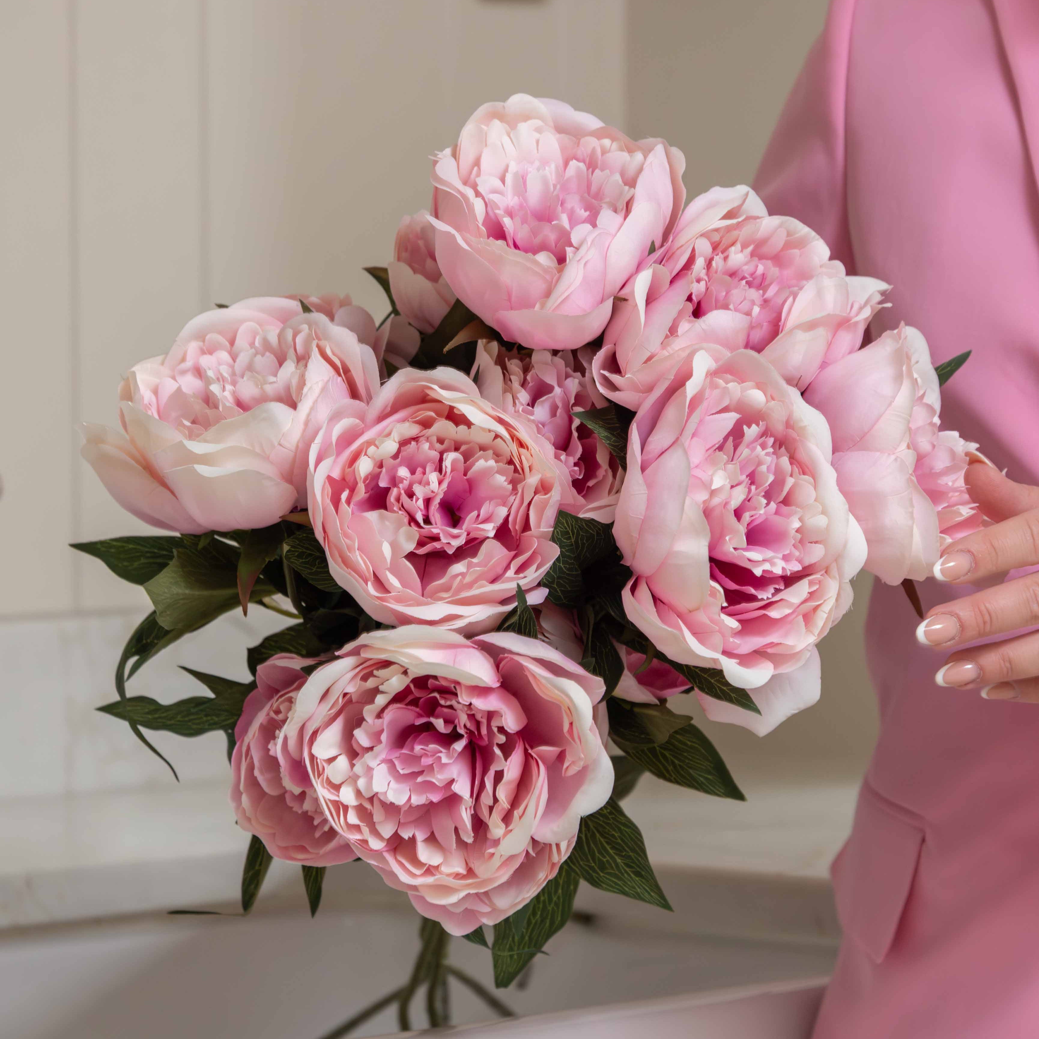 lifelike, real-touch Peony stems in a delicate shade of blush pink. Each stem boasts two fully open blooms full of petals, along with a budding side shoot and gorgeous green foliage.

Each petal is meticulously hand-crafted and hand-painted.&nbsp;