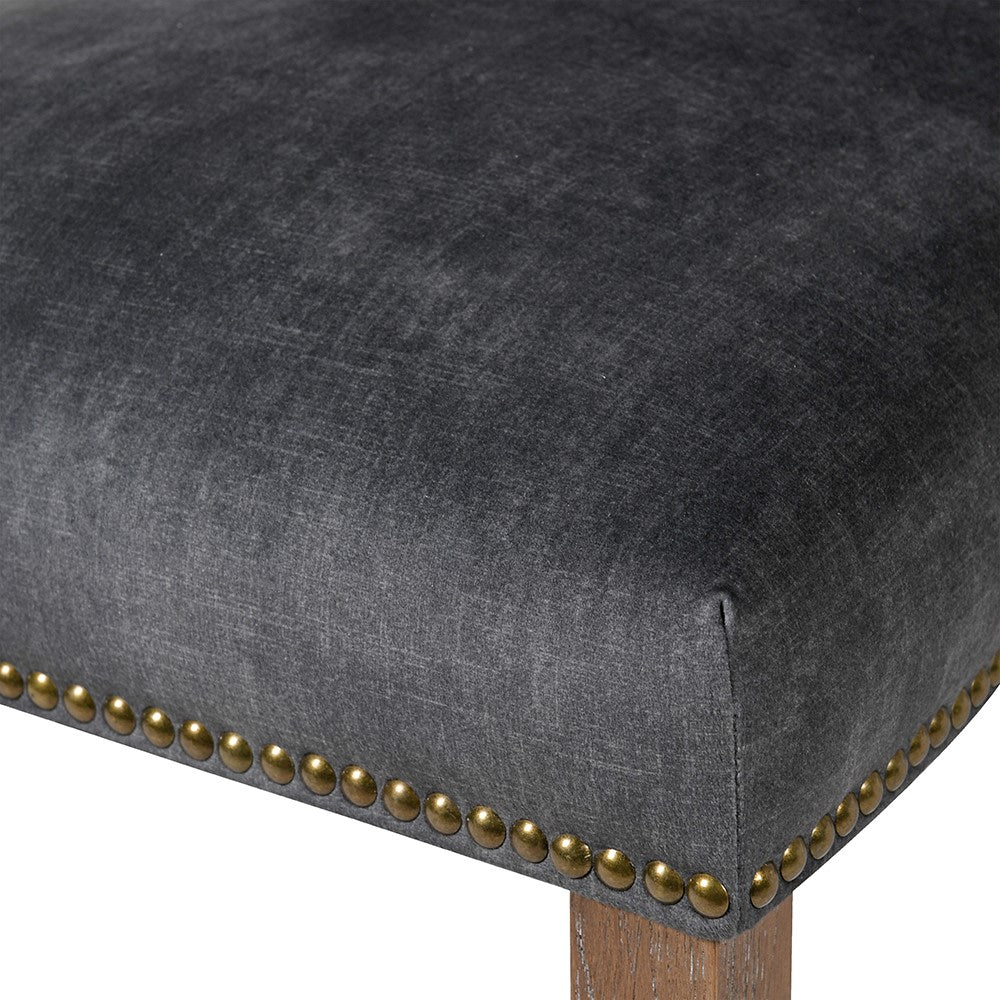 A stunning velvet chair in rich charcoal with brass stud detailing.