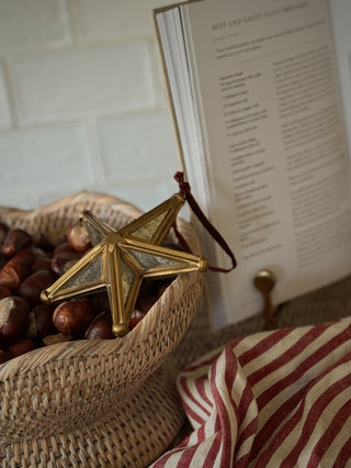 Scalloped rattan bowl of chestnuts with a gold star, open cookbook and striped tea towel