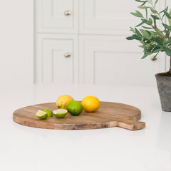 A large round breadboard made of recycled elm. Shown with some whole lemons and wedges of lime resting near the protruding handle