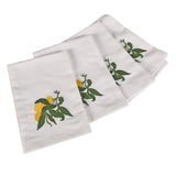 Set of four white cotton napkins with embroidered lemon and green leaf design folded for table setting
