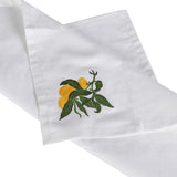 Set of four white cotton napkins with embroidered lemon and green leaf design folded for table setting