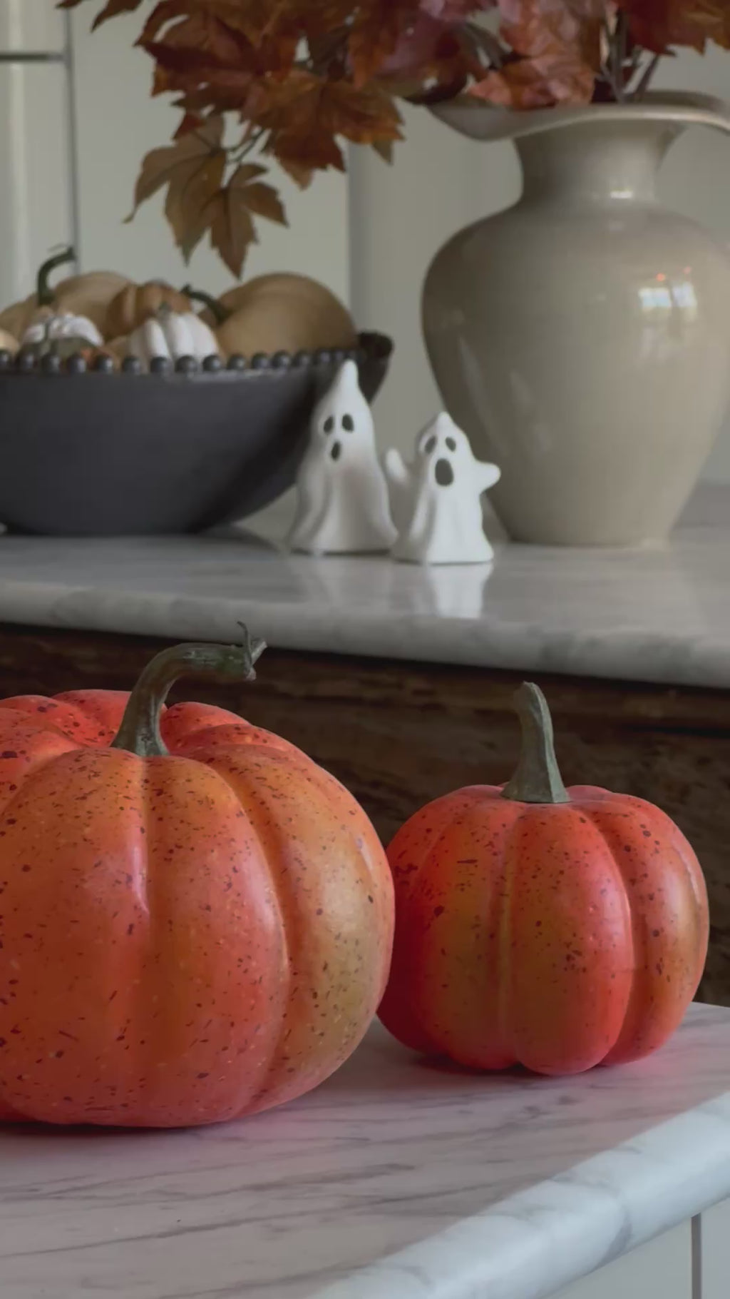 Autumn shelf styled with faux pumpkins, a stoneware vase and autumn leaves