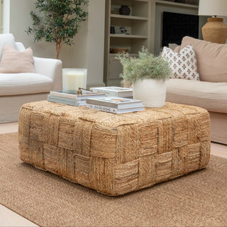 Marrakech 90 by 90cm square jute coffee table with chunky handwoven checkerboard weave in natural tone, styled with books, candle and white planter in a neutral living room