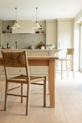Kitchen with wooden dining table and chairs, light-colored cabinets, and a backsplash.
