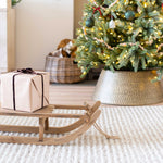 Wrapped gift sitting on wooden sleigh, under the Christmas tree