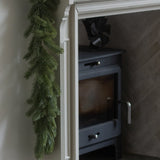 White fireplace with green garland and candles on a white wall