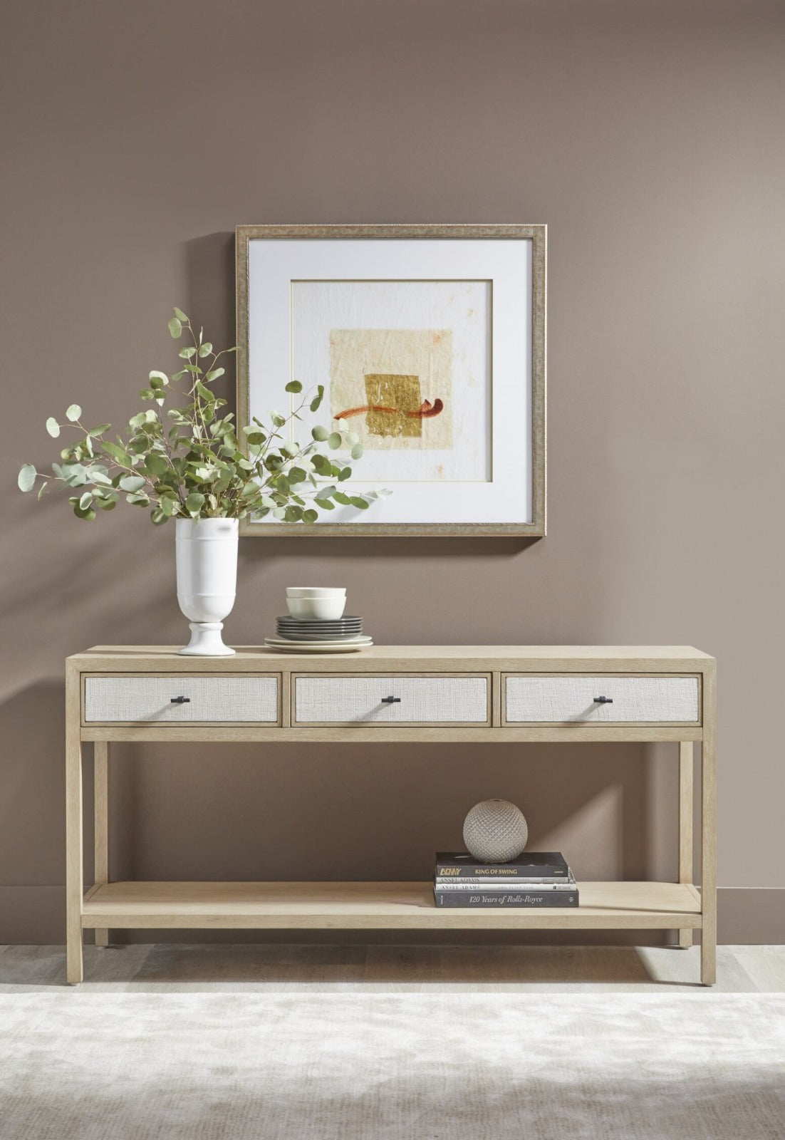 Tranquility light oak console table styled in a hallway with three linen-weave drawers and lower shelf