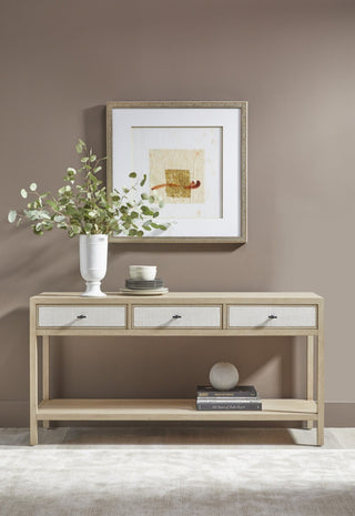 Tranquility light oak console table styled in a hallway with three linen-weave drawers and lower shelf