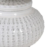 This white ceramic lamp base features a unique pattern reminiscent of an urchin, accompanied by a coordinating linen shade.