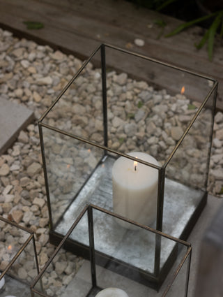 Small Whitstable hurricane lantern filled with three lit tealights on a paved outdoor step