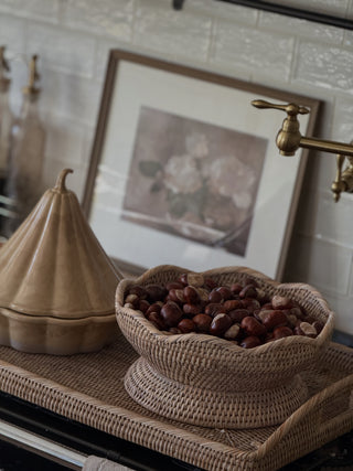 Close up of the grey wash rattan tray holding a scalloped rattan bowl of chestnuts