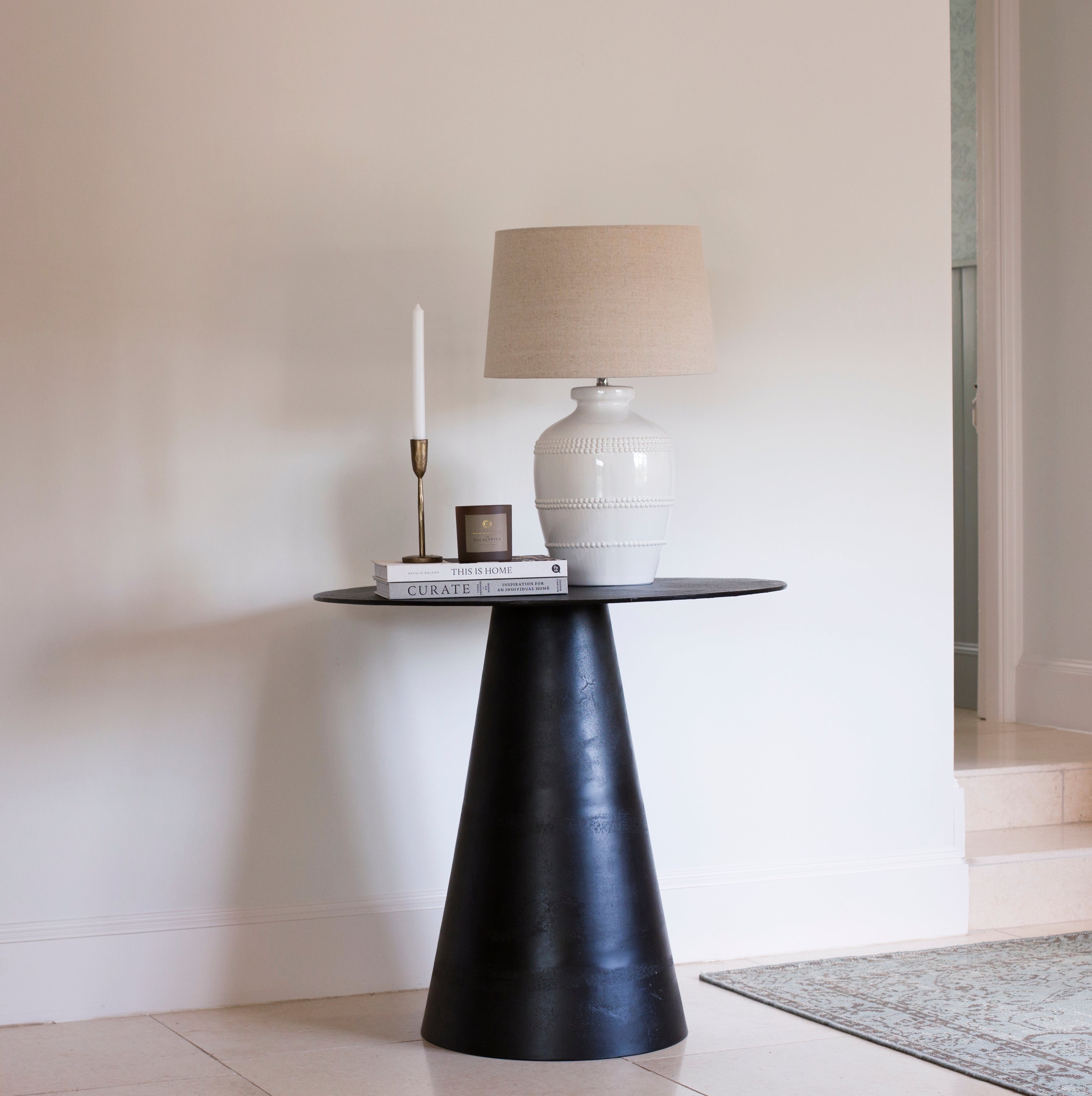 This luxuriously crafted lamp features a white ceramic base adorned with intricate beading, and accompanied by a natural linen shade.