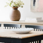 White ceramic bobble bowl on a dining table with books and a vase in the background