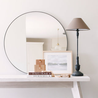 Pembury black table lamp styled on a whitewashed console table alongside a round black-framed mirror, stacked books, framed art and woven storage boxes