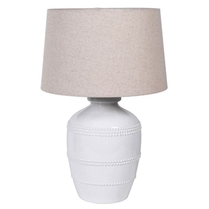 This luxuriously crafted lamp features a white ceramic base adorned with intricate beading, and accompanied by a natural linen shade.