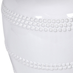 This luxuriously crafted lamp features a white ceramic base adorned with intricate beading, and accompanied by a natural linen shade.