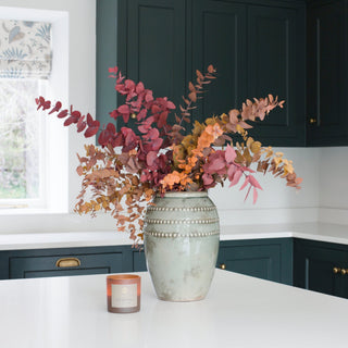 Decorative vase with autumn-themed leaves on a kitchen counter