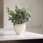 A bouquet of berry and green eucalyptus in a white vase