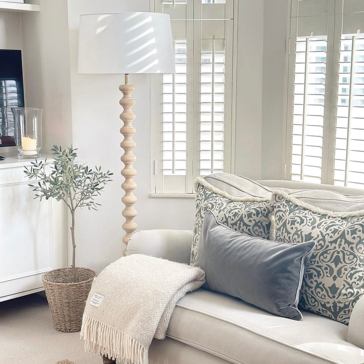 A stunning floor lamp in a beautiful turned pale wood complete with off white linen shade.